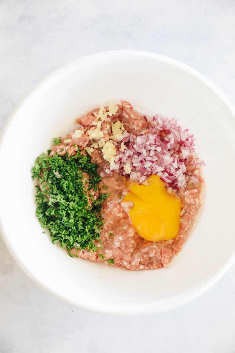 ingredients for turkey burgers in a large white bowl.