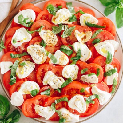 tomato burrata salad on a large plate with fresh tomatoes, burrata, basil, olive oil and salt and pepper.