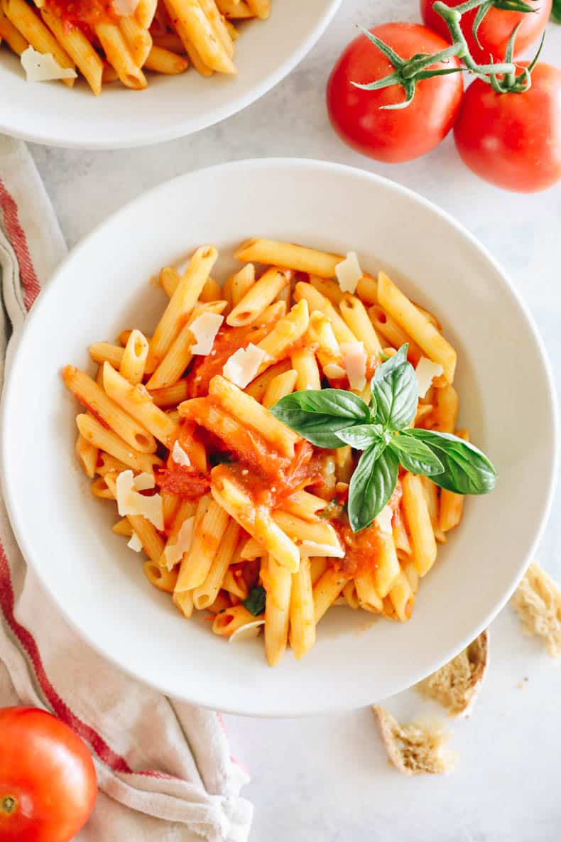 Home made tomato sauce on penne pasta in a white shallow bowl.