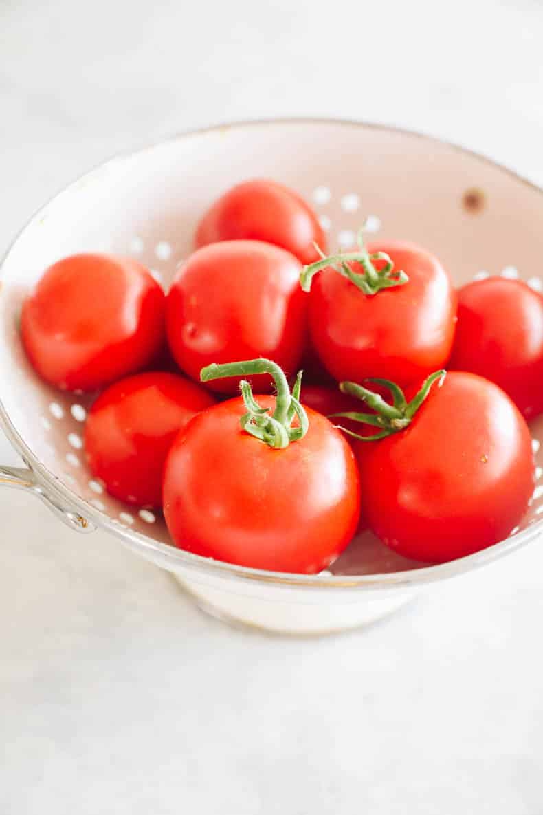 Fresh vine tomatoes in a white colander.