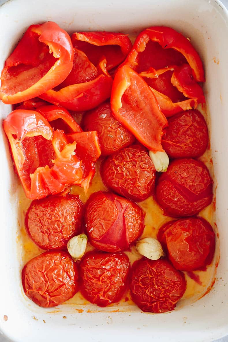 steamed roasted red peppers, tomatoes and garlic in a baking dish.