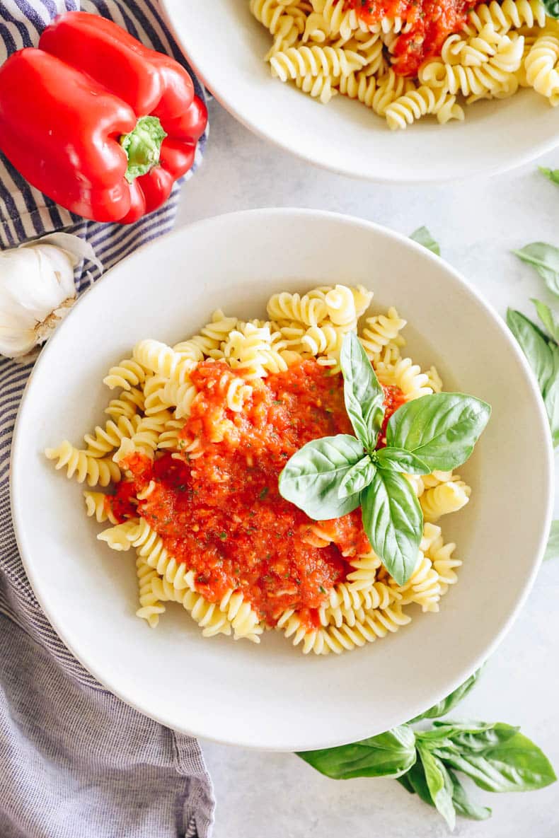 roasted red pepper pasta in a white shallow bowl with basil.