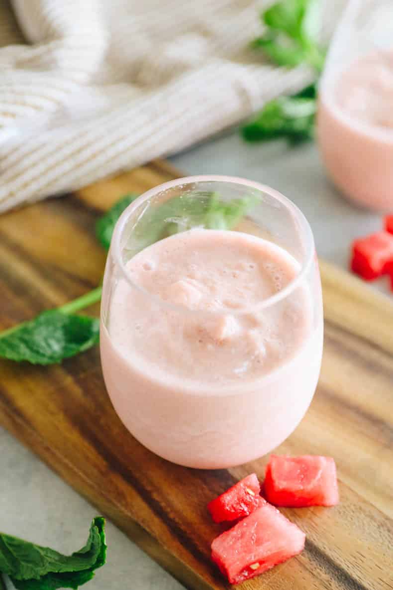 watermelon smoothie in a wine glass with fresh watermelon