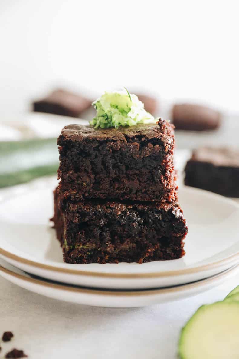 zucchini brownies stacked on white plates.