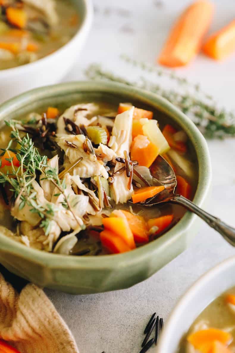 Chicken and wild rice soup in a green bowl with a spoon.