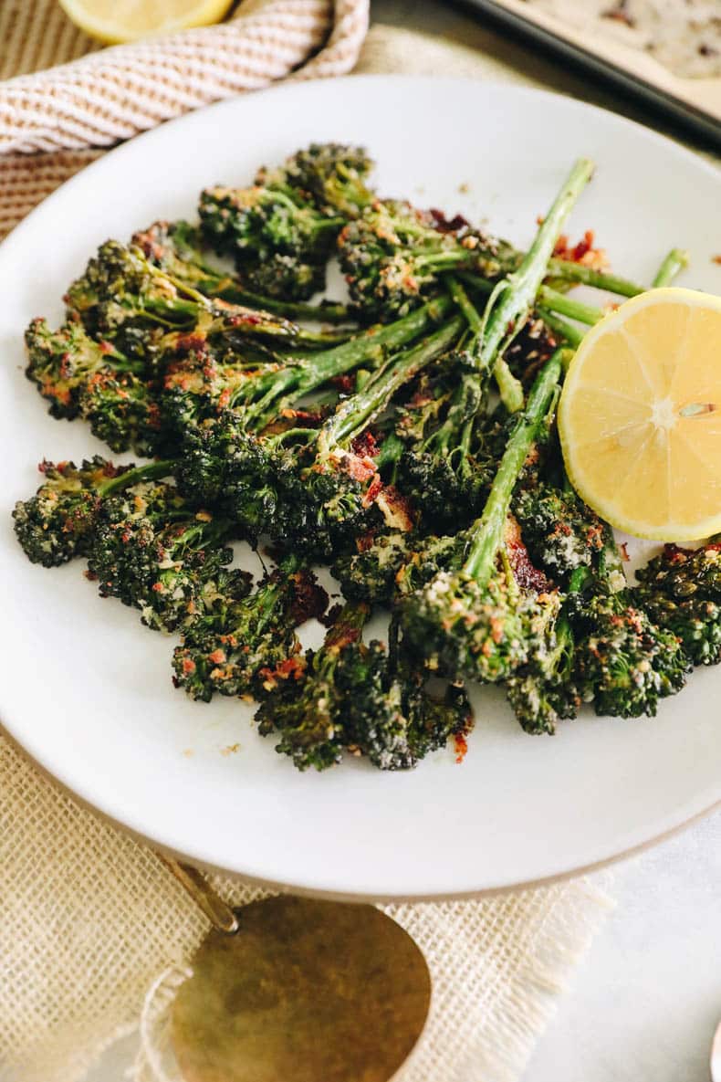 roasted broccolini on a white plate with lemon.