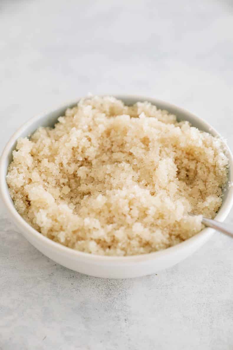 sugar and melted coconut oil mixed together in a white bowl to make DIY sugar scrub.