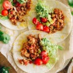 turkey tacos on white corn tortillas with ground turkey meat, tomatoes, guacamole and shredded lettuce.