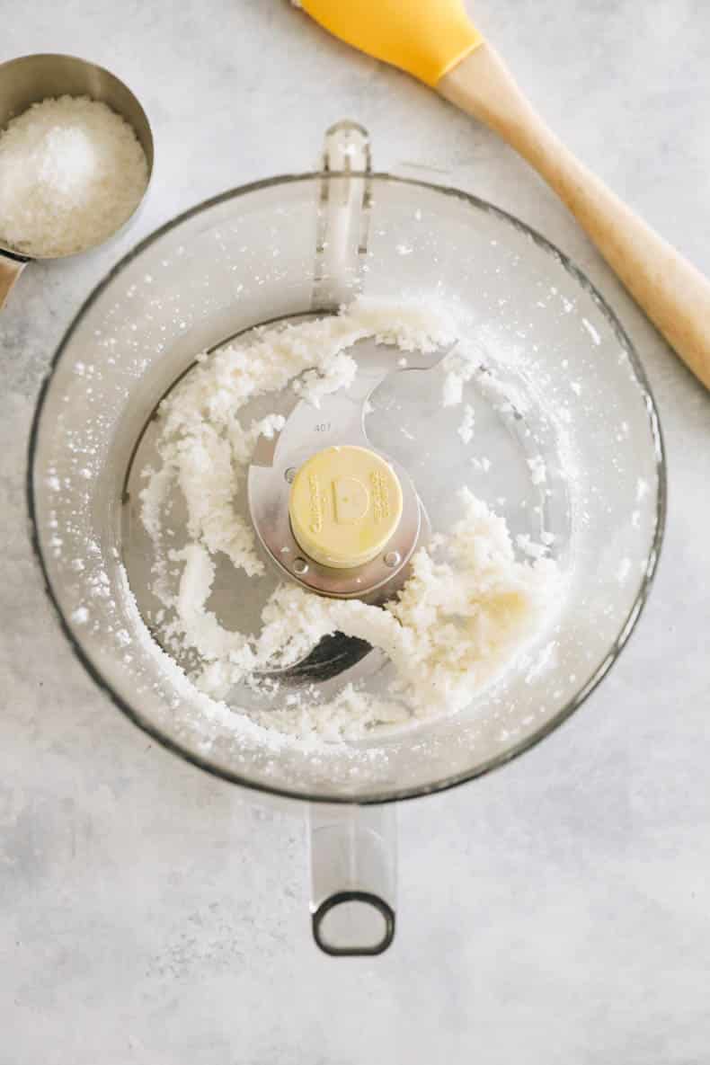 shredded coconut broken down in a food processor bowl.