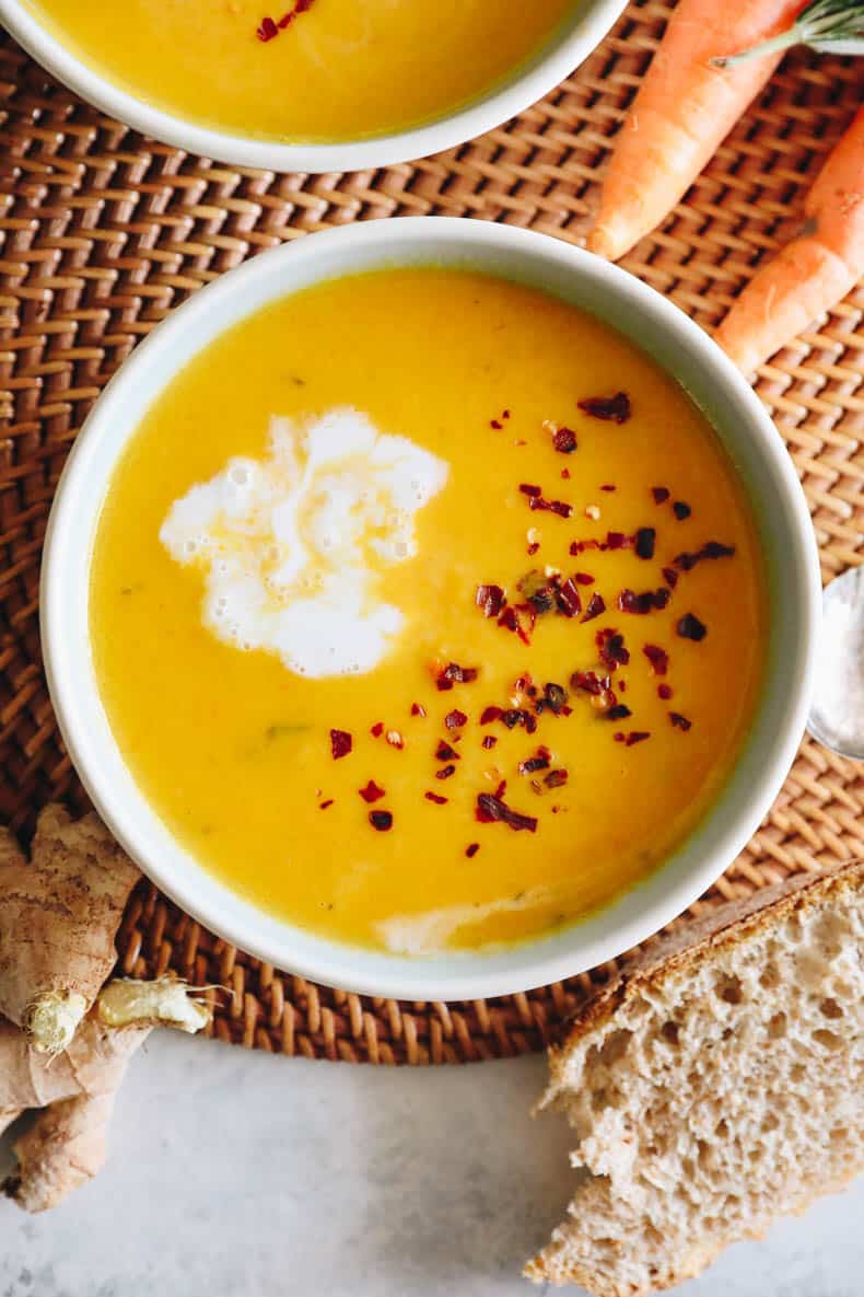 overhead image of ginger carrot soup with red pepper flakes and coconut cream.