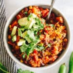 the ultimate healthy chili recipe in a white bowl with various toppings.