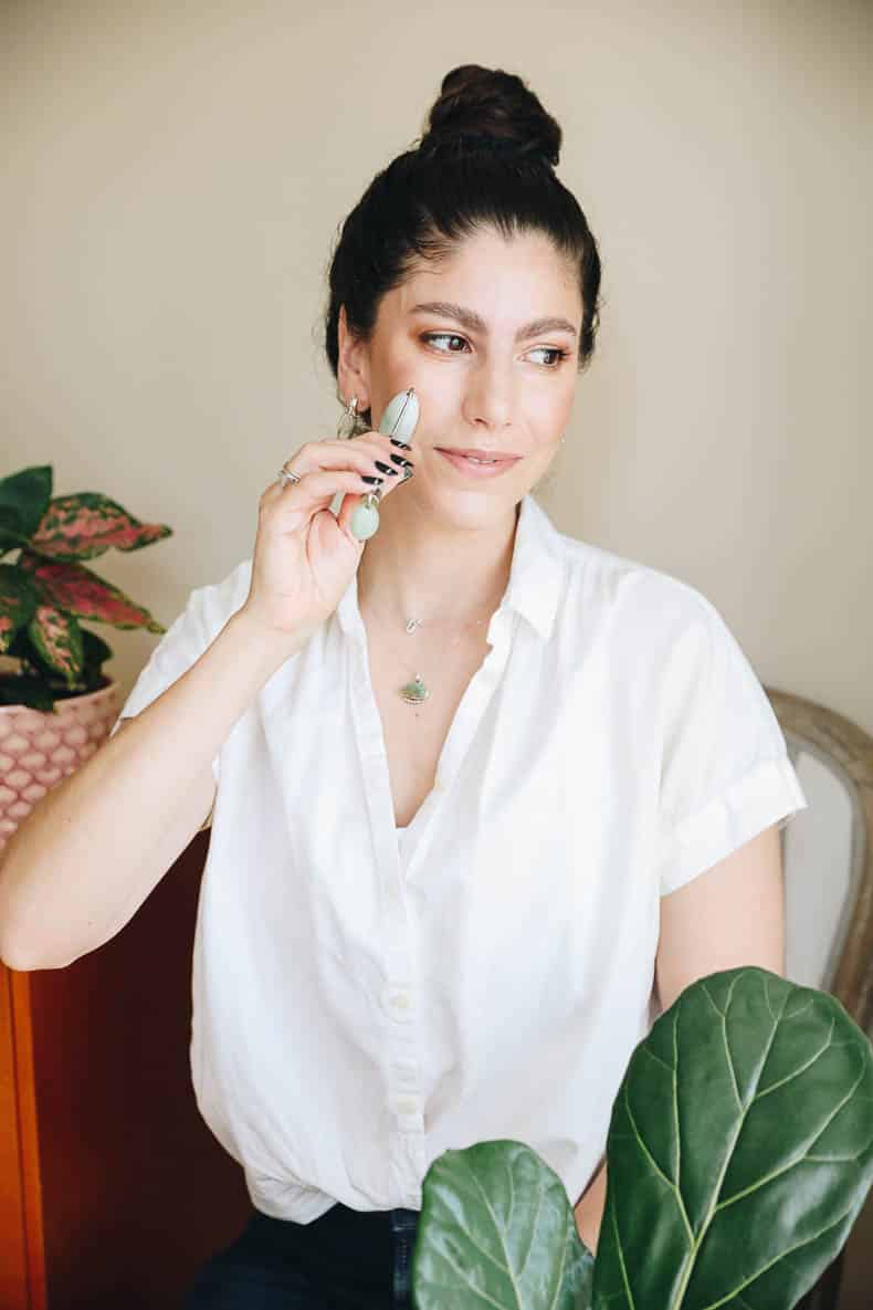 woman using a jade roller on her face.