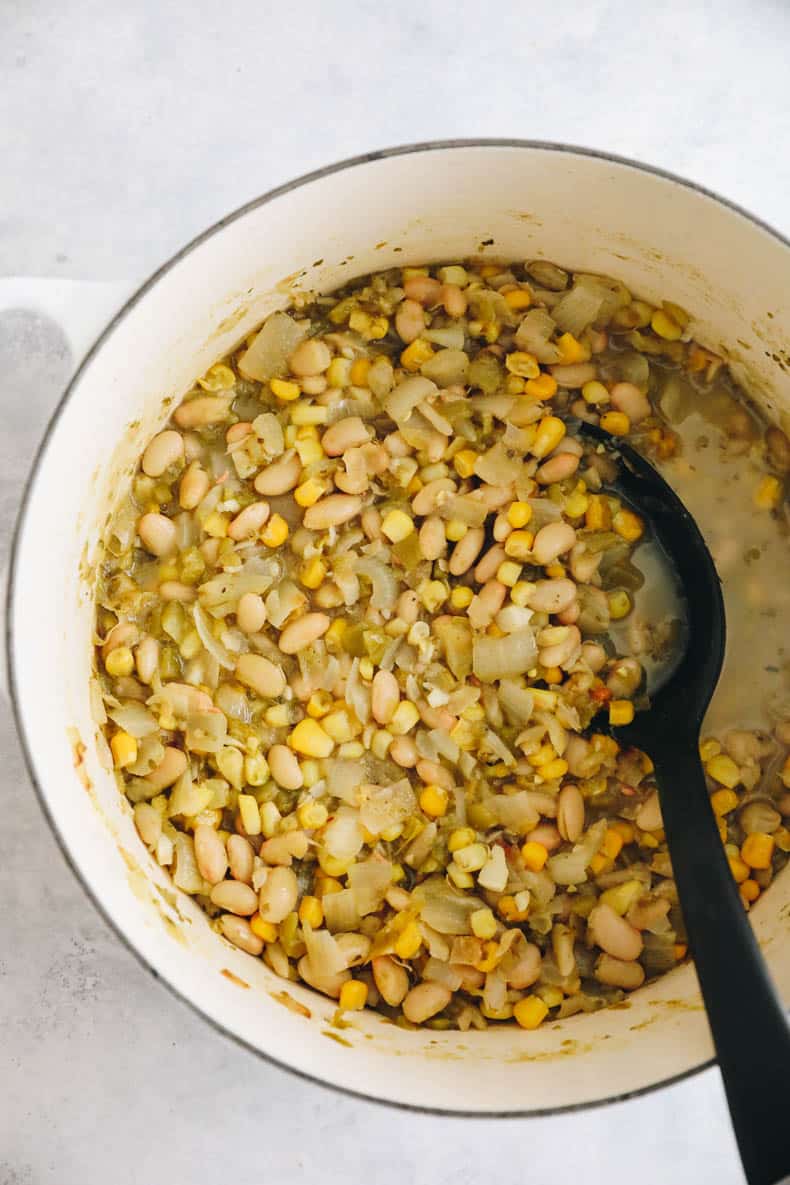 white bean chili simmering in a white dutch oven.