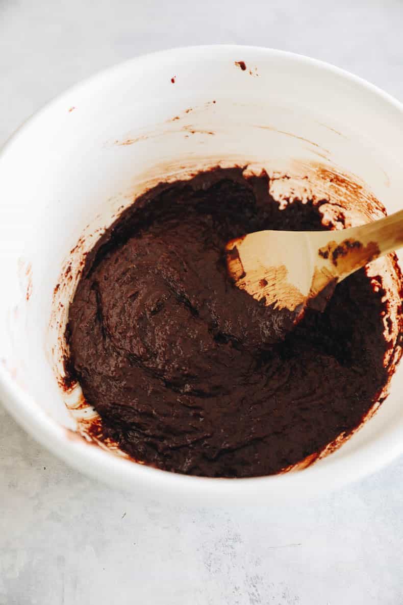 almond flour brownie batter in a white bowl with a wooden spoon.