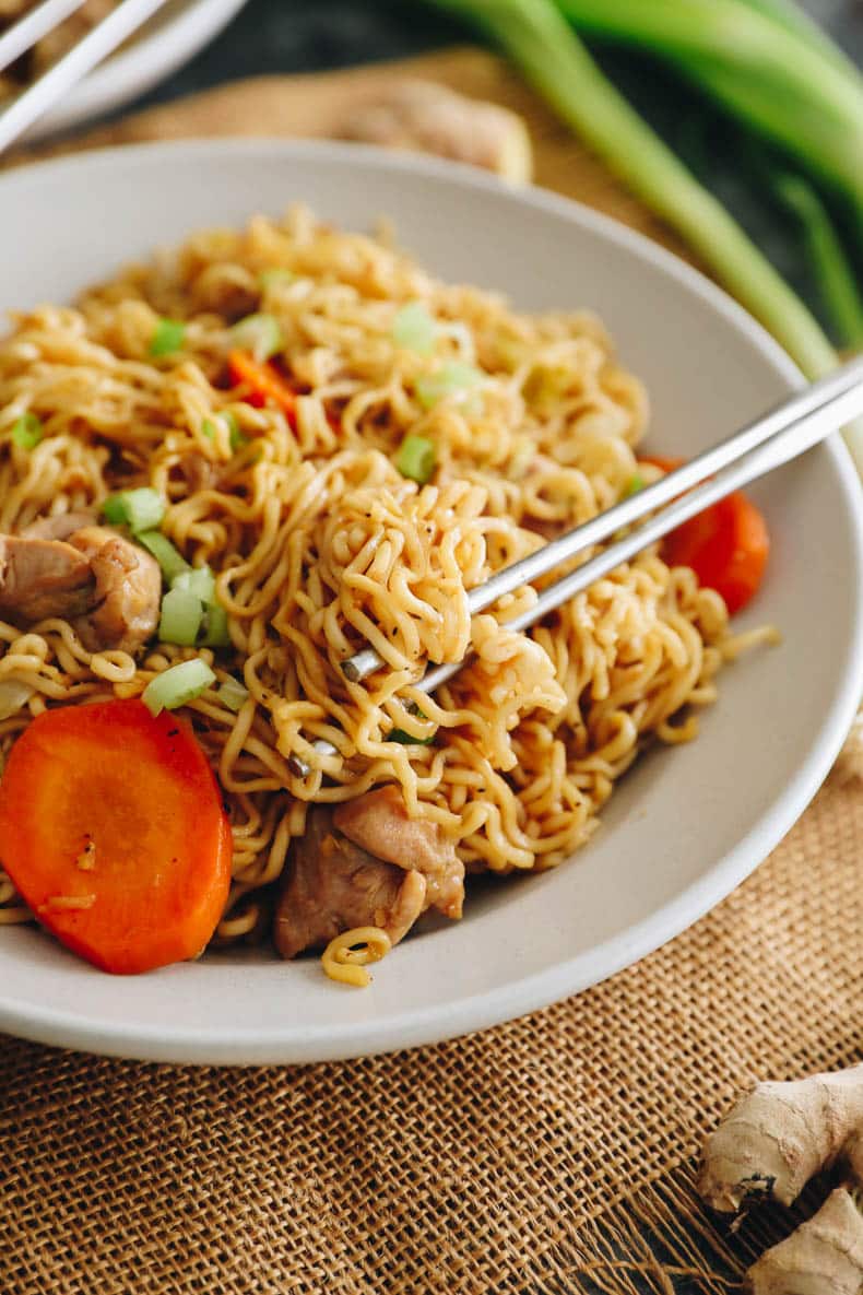 chicken chow mein in a white shallow bowl with silver chopsticks.