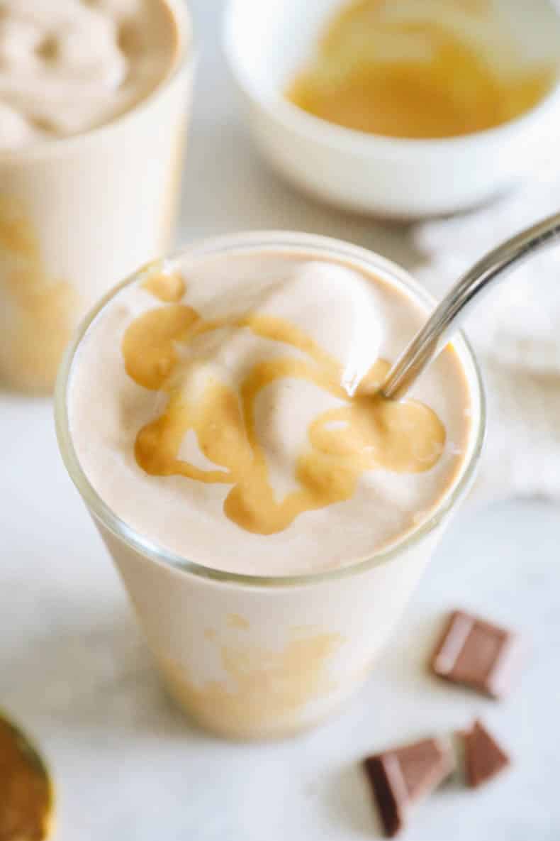 chocolate peanut butter smoothie with drizzled peanut butter in a clear glass.