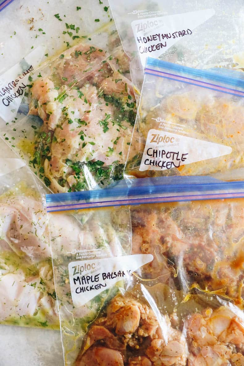 overhead of 5 ziploc bags with different chicken thigh marinade recipes in each.