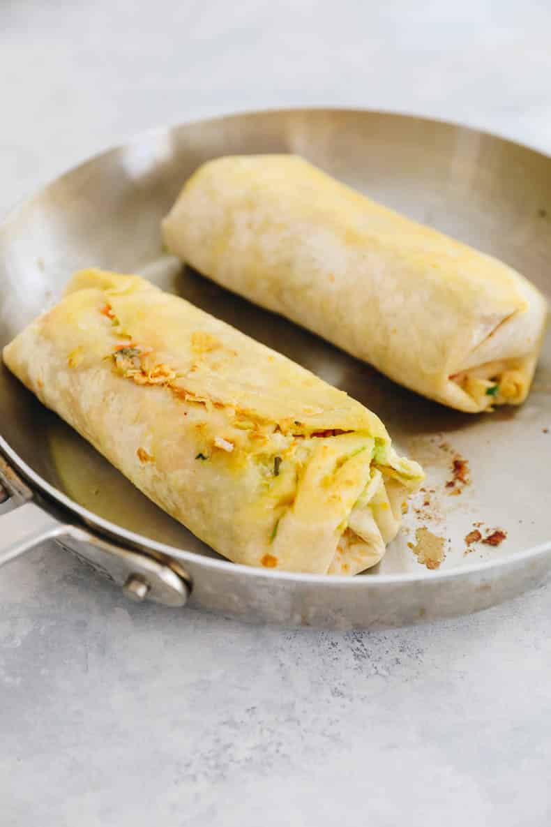 pan fried chicken burritos in a skillet.