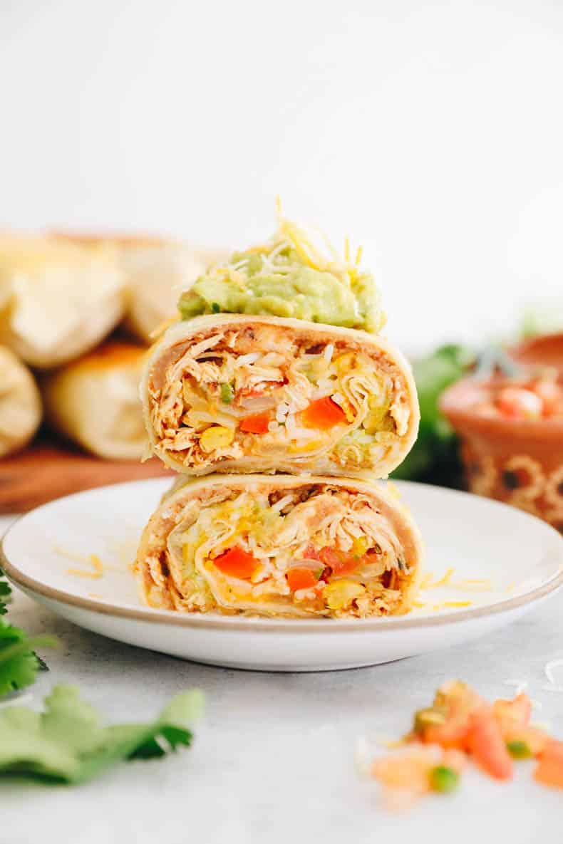 chicken burrito recipe cut in half and stacked on top of one another with guac and cheese.