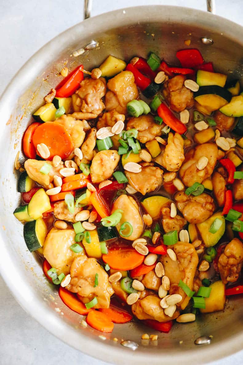 copycat panda express kung pao chicken cooked in a wok and topped with green onions and peanuts.