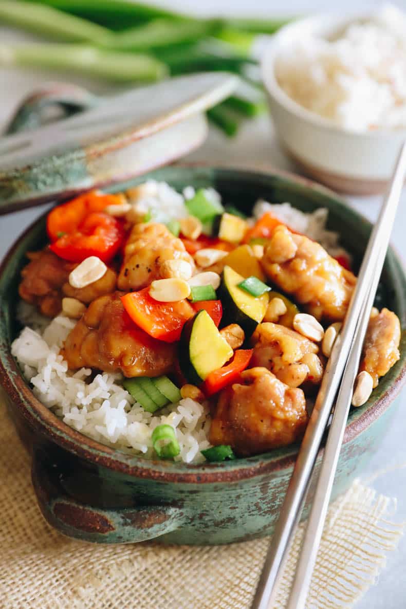 kung pao chicken over rice in a green bowl.