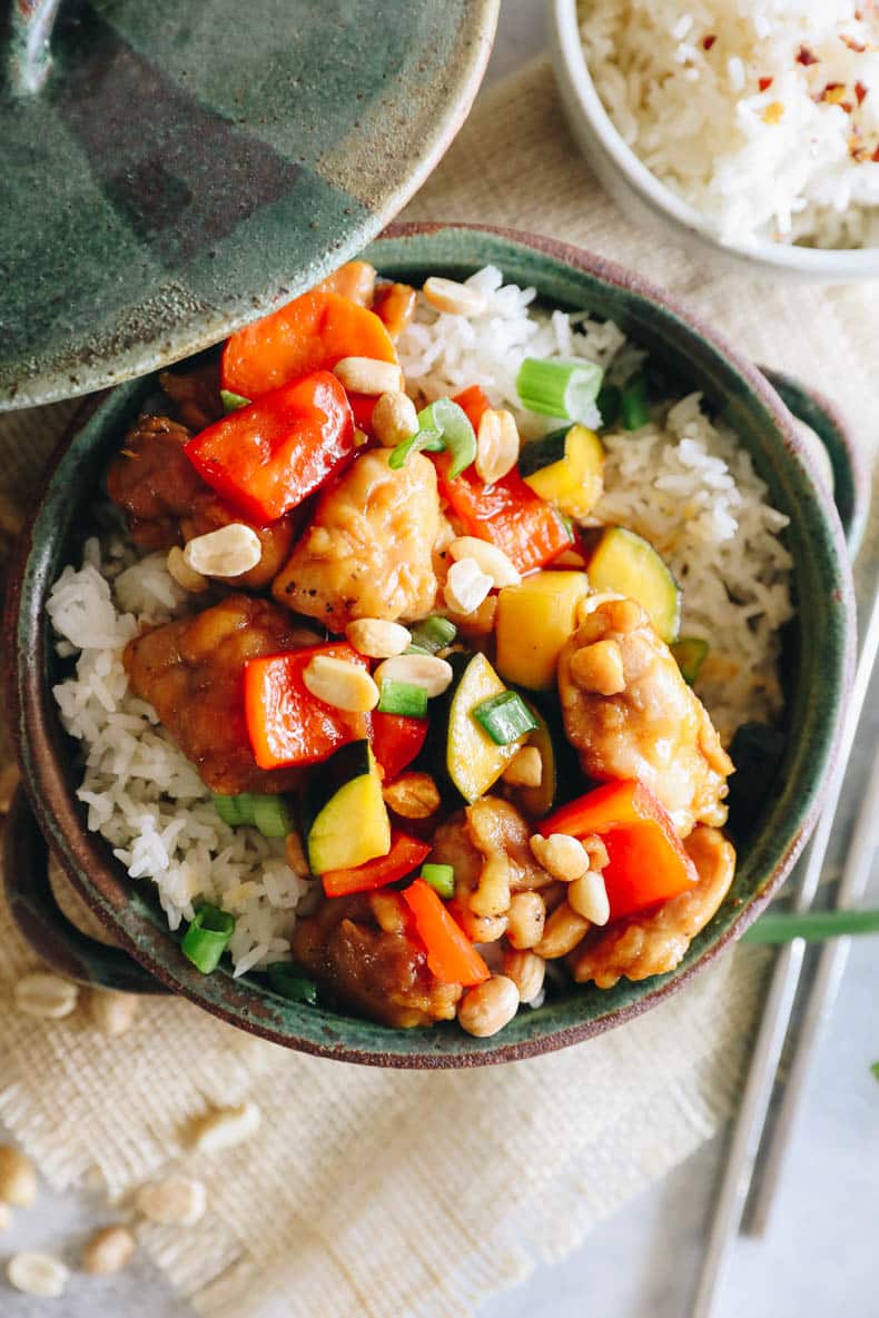 panda express copycat kung pao chicken recipe over rice in a green bowl with chopsticks.