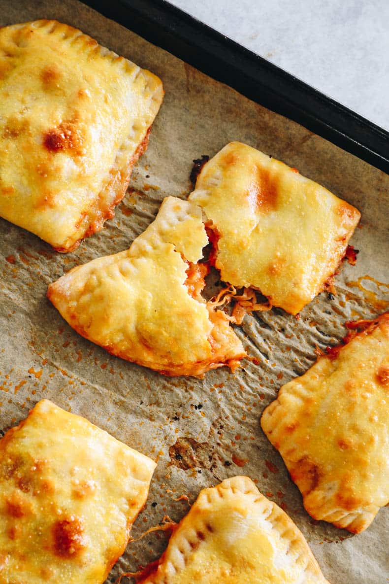 close-up of pizza pocket on a baking sheet with cheese oozing out.