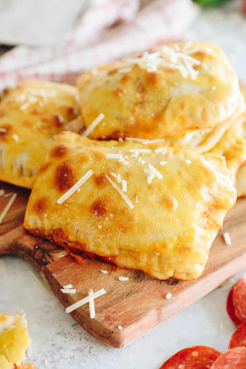 pizza pocket on a cutting board topped with parmesan cheese.