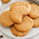 healthy peanut butter cookies on a plate with a bite taken out of the top cookie.
